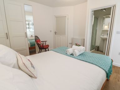 A bedroom with a bed folded towels on a blue blanket a chair a wardrobe and an open door to a bathroom at Tremar in Carbis Bay