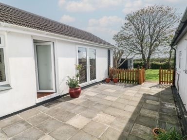 A patio with stone tiles wooden gates and potted plants outside a white building at Tremar Carbis Bay