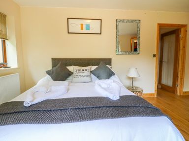 A bedroom with a bed pillows and towels near a window and a lamp at Dorado Lodge in Thorpe-on-the-Hill