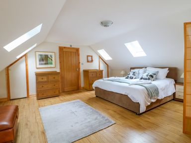 A bedroom with a bed two wooden dressers a rug and skylights at Dorado Lodge in Thorpe-on-the-Hill