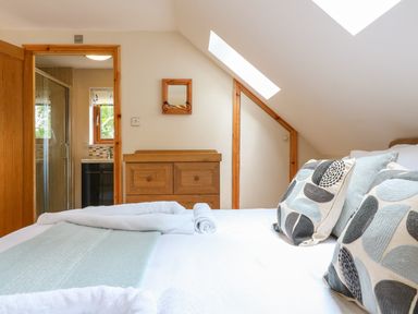 A bedroom with a bed with pillows and towels a wooden dresser and a door leading to a bathroom at Dorado Lodge in Thorpe-on-the-Hill