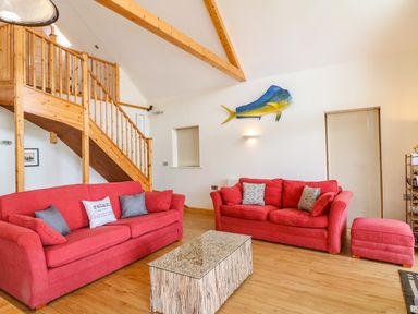 A living room with red sofas wooden staircase and a fish decoration on the wall at Dorado Lodge in Thorpe-on-the-Hill