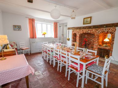 A dining room with a long wooden table set for a meal and a brick fireplace at Southrepps Lodge in Southrepps