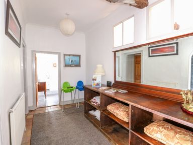 A hallway with a long wooden cabinet with cushions and a large mirror and two high chairs at Southrepps Lodge in Southrepps