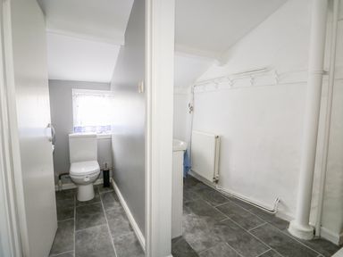 A bathroom with a toilet and a separate area with a sink radiator and hooks on the wall at Southrepps Lodge in Southrepps