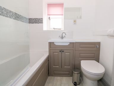 A bathroom with a bathtub a sink toilet and a small window at Southrepps Lodge in Southrepps
