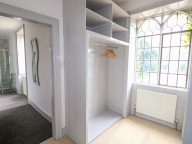 A wardrobe with hangers next to a window and radiator in a room at Southrepps Lodge in Southrepps