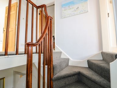 A staircase with wooden railing and gray carpet at Southrepps Lodge in Southrepps