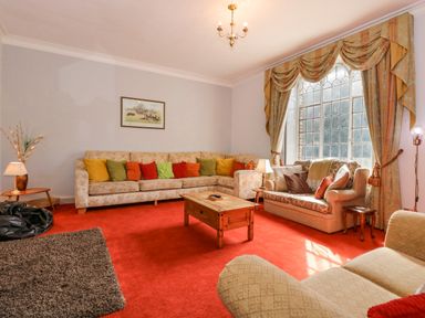 A living room with colorful cushions on sofas and a wooden coffee table at Southrepps Lodge in Southrepps