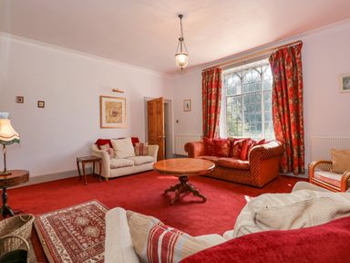 A living room with red carpet couches and a wooden coffee table at Southrepps Lodge in Southrepps