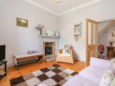 A living room with a fireplace a wooden coffee table a wicker chair and a purple sofa at Southrepps Lodge in Southrepps