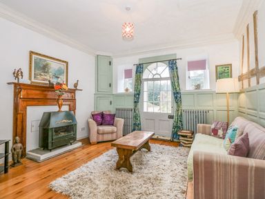A living room with armchairs sofa wooden coffee table and fireplace at Southrepps Lodge in Southrepps
