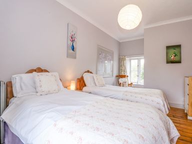 A bedroom with two single beds a window and paintings on the wall at Southrepps Lodge in Southrepps