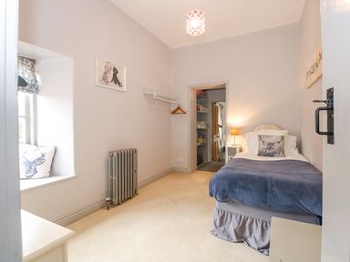 A bedroom with a single bed beside a nightstand lamp and a window seat with cushions at Southrepps Lodge in Southrepps