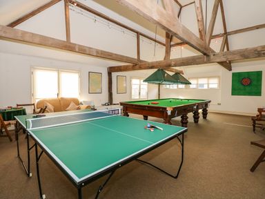 A game room with a ping pong table and a snooker table under wooden beams at Southrepps Lodge in Southrepps