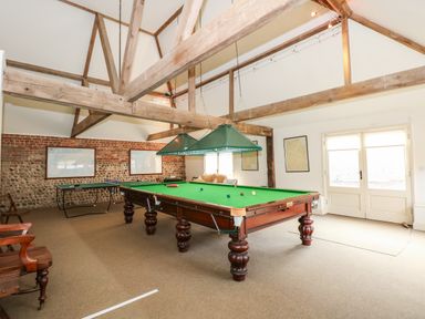 A game room with a snooker table ping pong table wooden chairs and framed pictures on walls at Southrepps Lodge in Southrepps