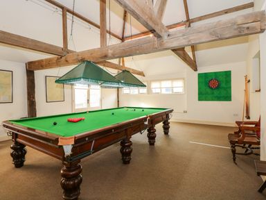 A game room with a snooker table and a dartboard on the wall at Southrepps Lodge in Southrepps