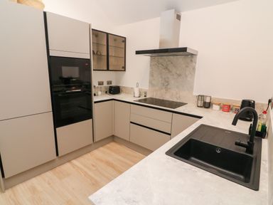 A modern kitchen with black appliances and a corner countertop at Sunshine Cottage in Preston under Scar near Leyburn
