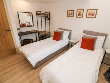 A bedroom with two single beds a desk with mirror and open wardrobe at Sunshine Cottage Preston under Scar near Leyburn
