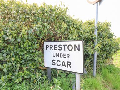 A road sign that says Preston under Scar with green bushes and grass around Sunshine Cottage Preston under Scar near Leyburn