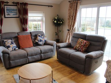 A living room with two gray sofas and a round wooden coffee table at Ellens Cottage in Mount Charles County Donegal