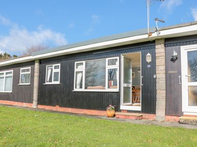 Exterior of a single-story building with black wooden walls and white framed windows at The Borrowers in Dartmouth