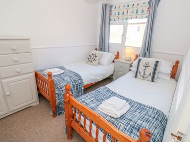A bedroom with two single wooden beds a nightstand with lamp and a chest of drawers at The Borrowers in Dartmouth