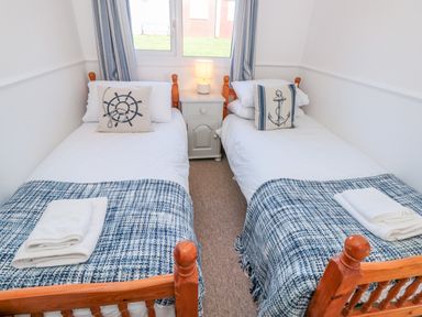 A bedroom with two single beds with blue patterned throws and nautical pillows at The Borrowers in Dartmouth