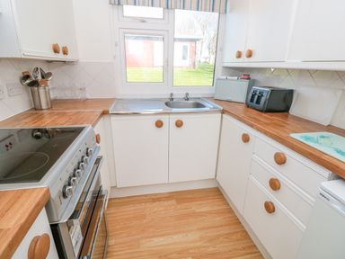 A kitchen with white cabinets wooden countertops a stainless steel oven and a sink under a window at The Borrowers in Dartmouth