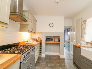 A kitchen with a stove oven microwave sink and wooden countertops at Brock Cottage in West Bay