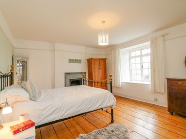 A bedroom with a bed bedside table wardrobe cabinet window and wooden floor at Brock Cottage in West Bay