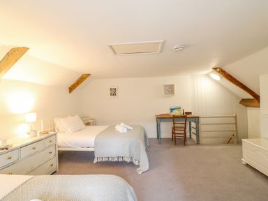 A bedroom with two single beds a chest of drawers a desk and chair in an attic room at Brock Cottage in West Bay