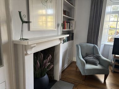 A living room with a fireplace and bookshelf at Brock Cottage in West Bay