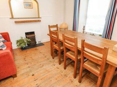 A dining area with a wooden table and chairs a red sofa and a small fireplace at Labour in Vain in St Ives