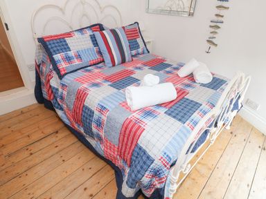 A bedroom with a metal bed frame wooden floor and a patchwork quilt at Labour in Vain in St Ives