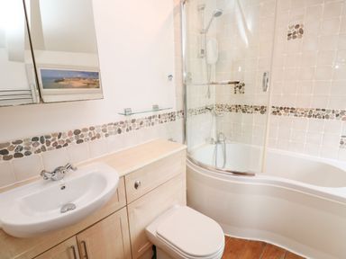 A bathroom with a sink, toilet, and bathtub with shower at Labour in Vain in St Ives