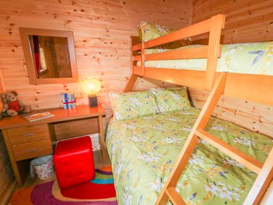A bedroom with wooden bunk beds a desk with a lamp books and a teddy bear at Alken Cabin in Bushmills County Antrim