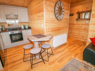 A small kitchen and dining area with wooden walls and floor at Alken Cabin in Bushmills County Antrim