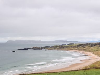 A beach with waves and rocky shoreline under a cloudy sky at Alken Cabin in Bushmills County Antrim