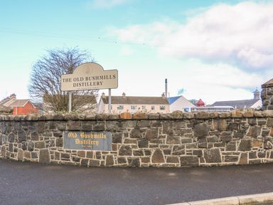 An entrance with stone wall and signs for The Old Bushmills Distillery in Bushmills County Antrim