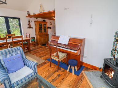 A living room with a piano and wooden furniture near a fireplace at The Mermaid in Dungloe County Donegal