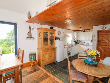 A kitchen with wooden furniture and ceiling and flowers on a round table at The Mermaid in Dungloe County Donegal