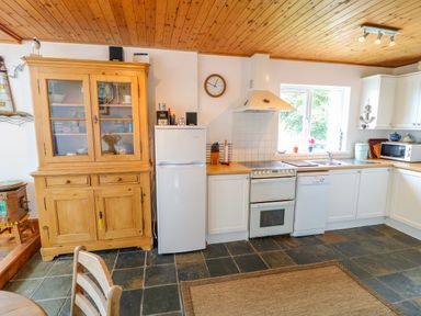 A kitchen with wooden cabinets a white refrigerator a stove dishwasher and a wooden cupboard at The Mermaid in Dungloe County Donegal