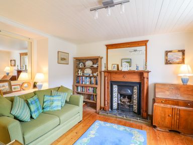 A living room with a green sofa and a wooden fireplace with a mirror above at The Mermaid in Dungloe County Donegal