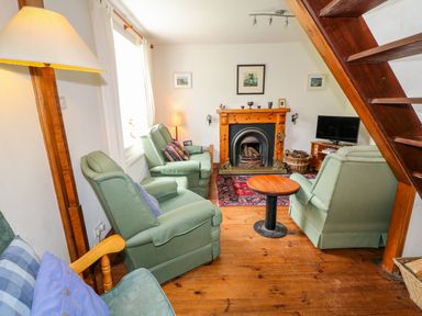 A living room with green armchairs a wooden coffee table a fireplace and a television at The Mermaid in Dungloe County Donegal