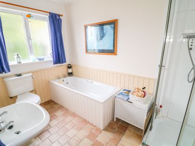 A bathroom with a bathtub sink toilet blue curtains and a shower at The Mermaid in Dungloe County Donegal