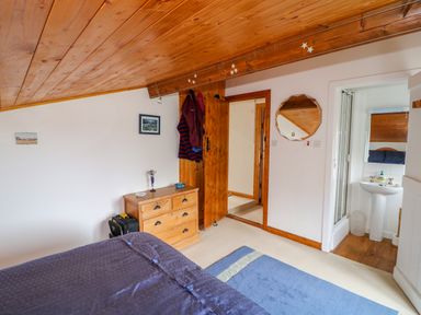 A bedroom with a wooden chest of drawers a bed a blue rug and an ensuite bathroom at The Mermaid in Dungloe County Donegal