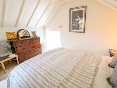 A bedroom with a bed a wooden dresser a chair and a framed picture on the wall at The Mermaid in Dungloe County Donegal