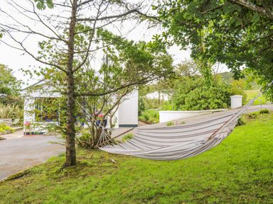 A hammock tied between two trees on a grassy area in front of a white house at The Mermaid in Dungloe County Donegal