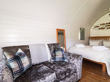 A room with a sofa and a bed with towels on top at The Lamb Shack in St Teath
